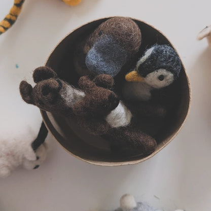 A collection of hand-felted animal toys, including a central nest of Kangaroo, Penguin, and Platypus , a yellow tiger at the top left, and a gray sheep at the bottom right, arranged on a white surface.